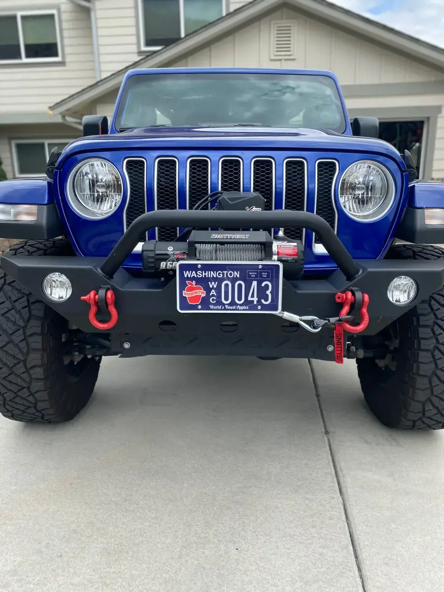 The front of a blue Jeep Wrangler fitted with a winch and a Washington Apples plate