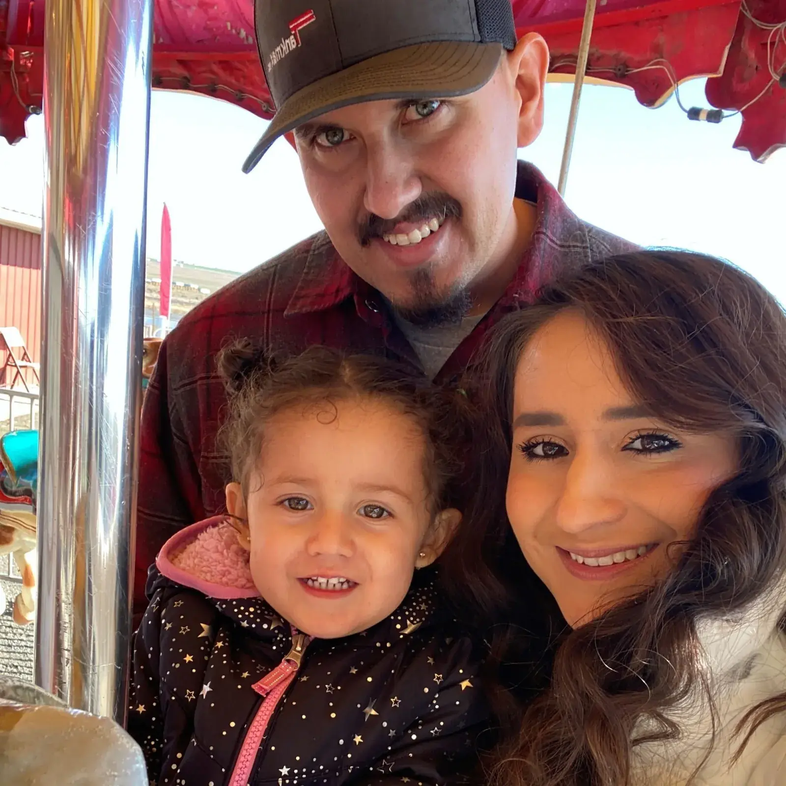 A man, a woman and a small child smiling together indoors