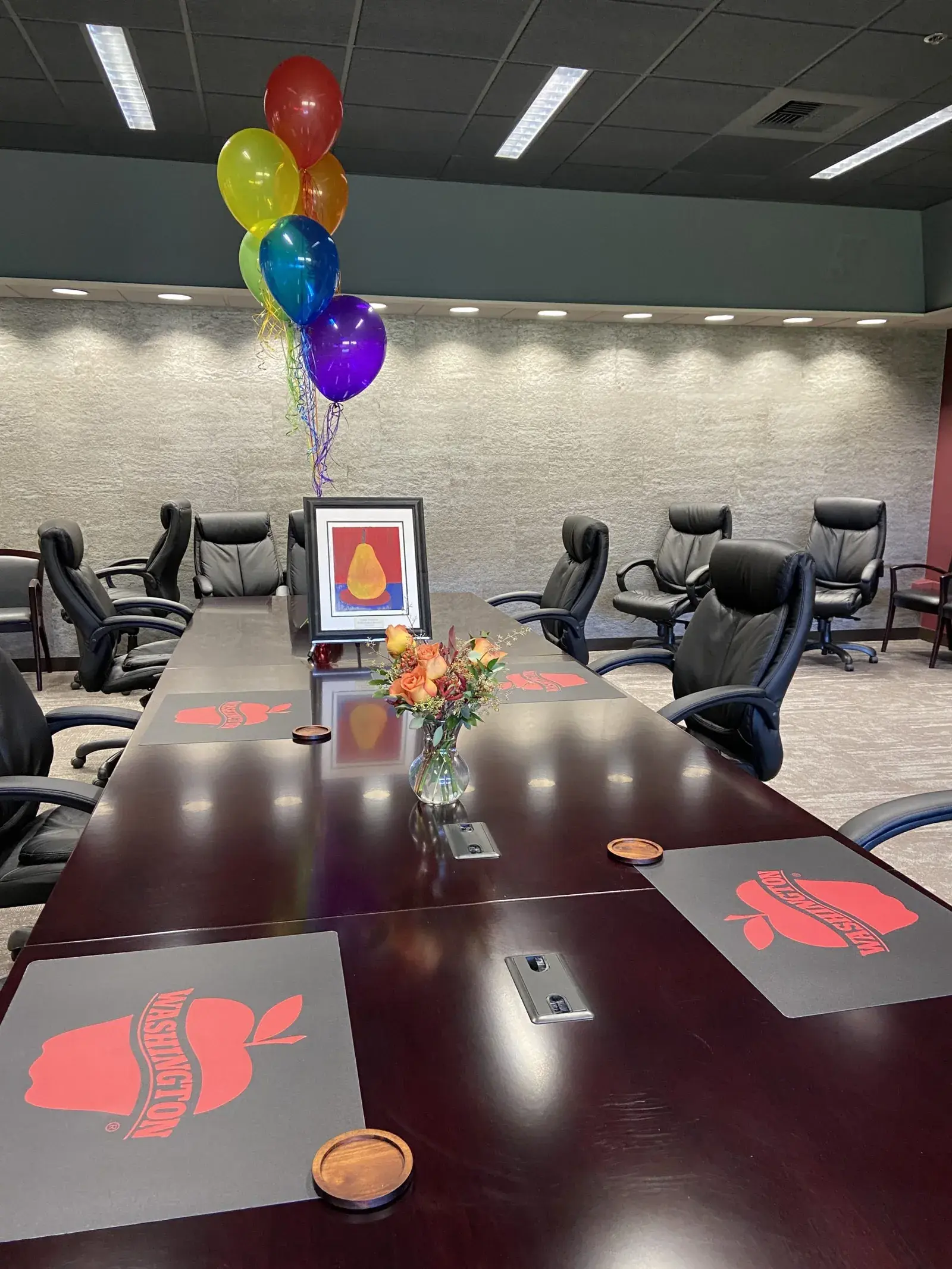 An empty boardroom set for a meeting, with balloons and a framed print