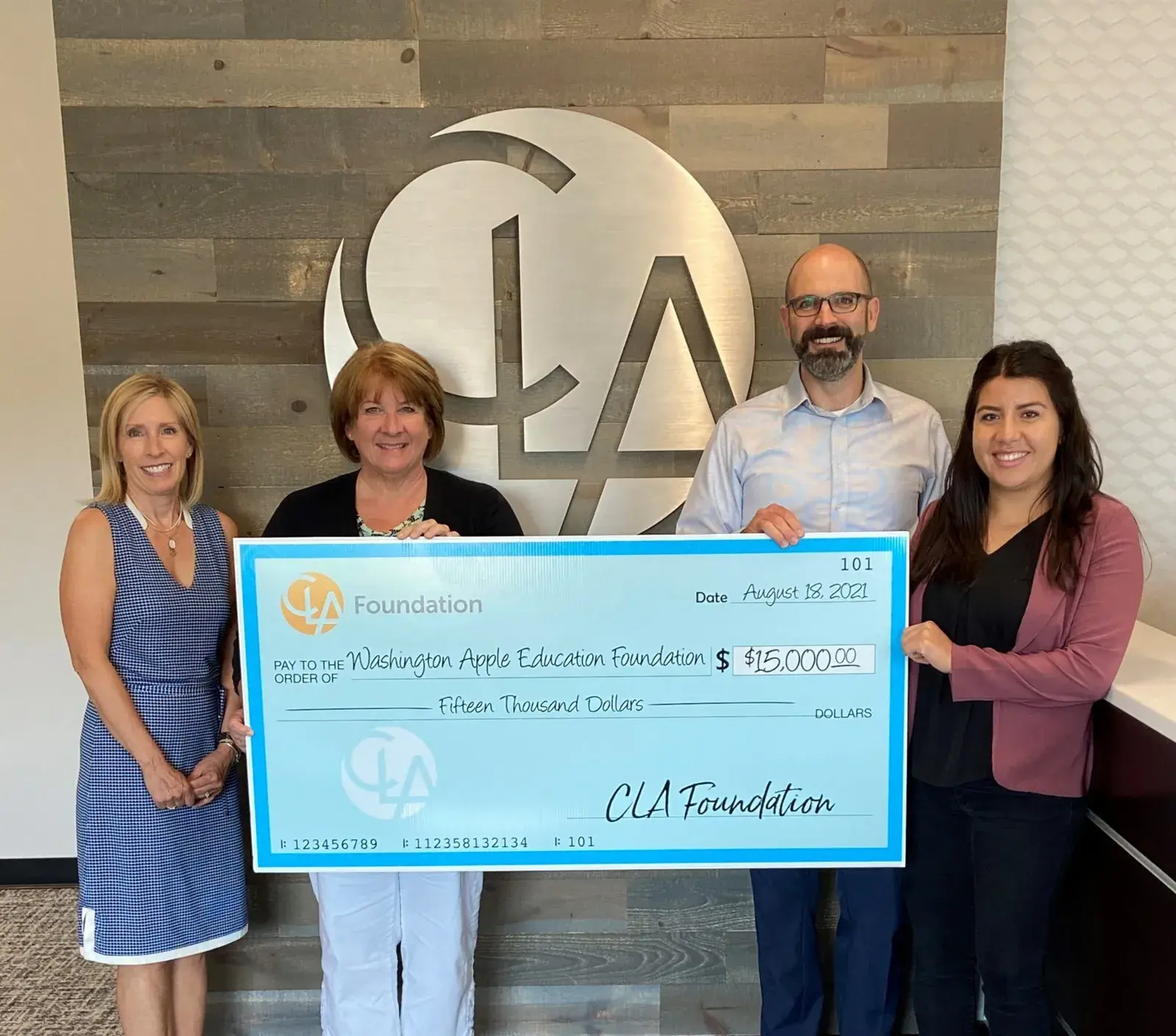 Five people holding an oversized CLA Foundation cheque for fifteen thousand dollars in front of the CLA logo