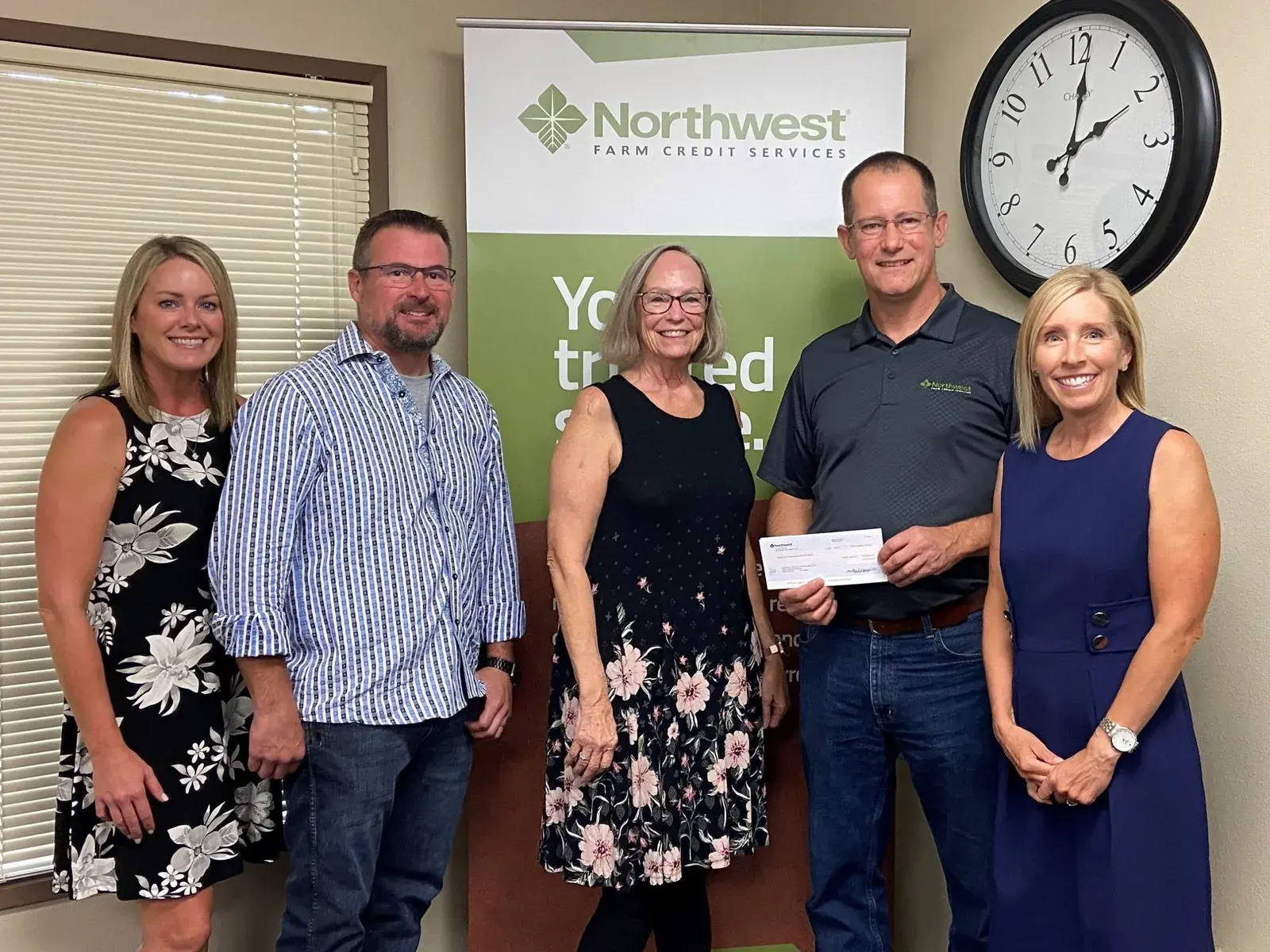 Five people holding a cheque together in a Northwest Farm Credit Services office