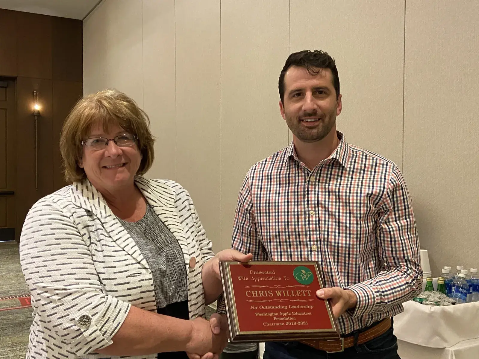 A woman and a man holding an engraved award plaque between them