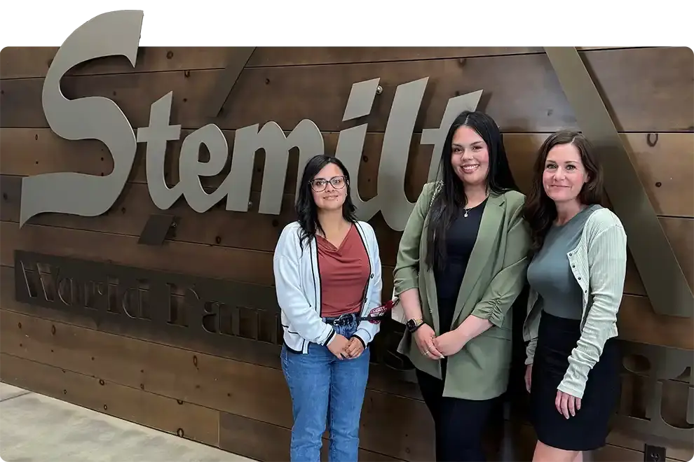 Three women in front of the Stemilt Growers sign during a WAEF career exploration day
