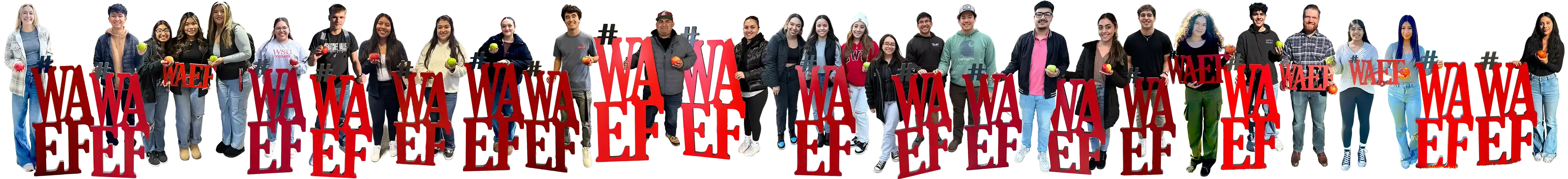 A long row of WAEF students holding apples, standing among tall red "#WAEF" letters
