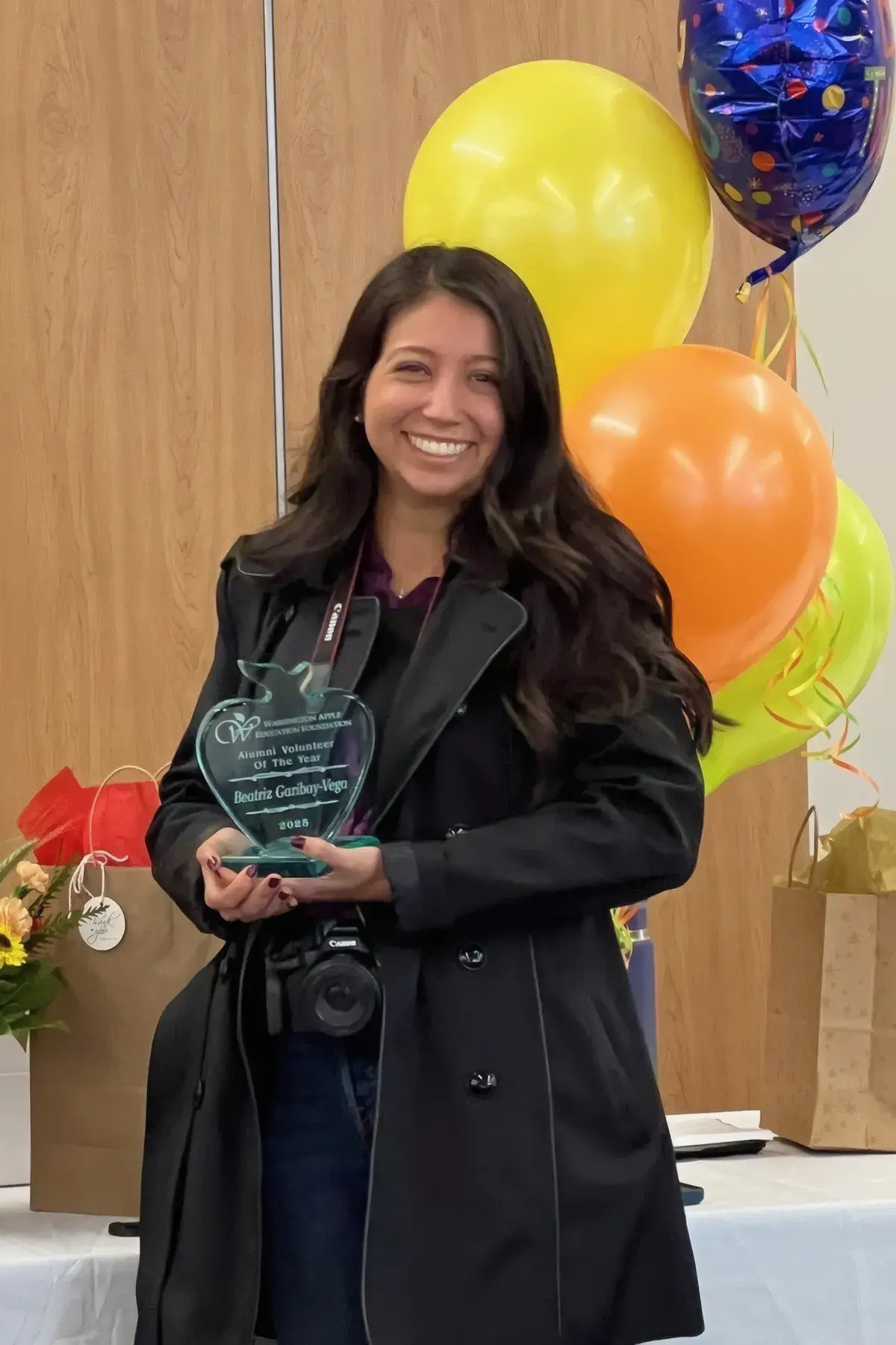 WAEF's Volunteer of the Year smiling with her glass award, balloons behind her