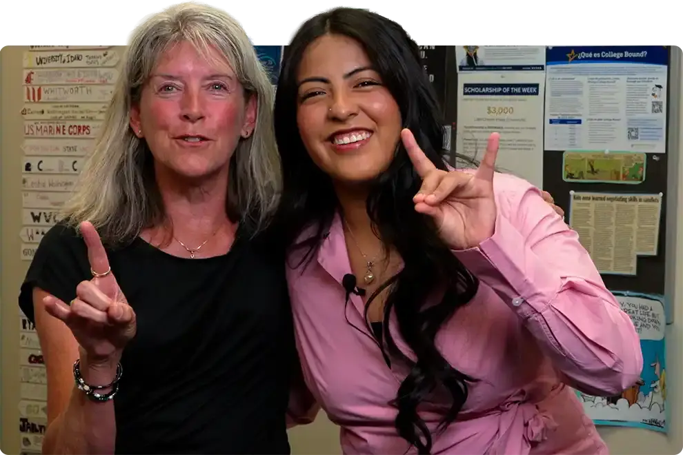 A school counselor and a WAEF student standing together in a counseling office, both smiling and pointing upward, a scholarship board on the wall behind them