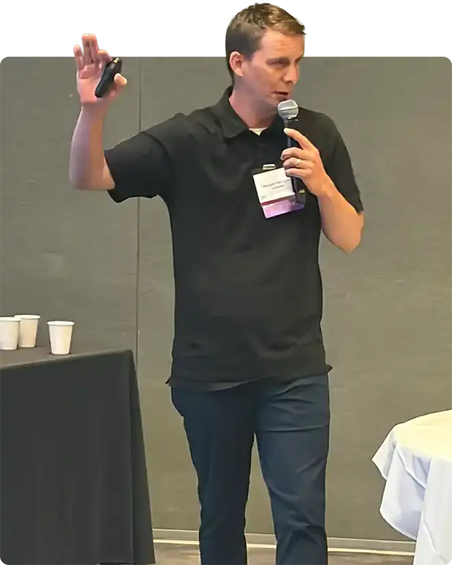 A speaker in a black polo with a microphone, one hand raised mid-sentence, leading a WAEF skills session