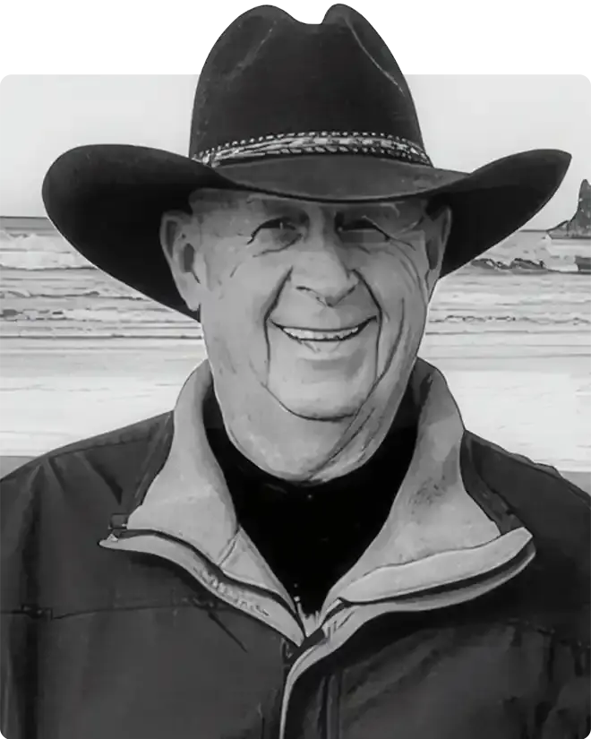 Junior (JR) Harris smiling in a black cowboy hat and dark jacket, photographed in black and white on a beach