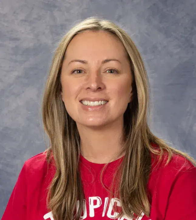 Robin Hansen, in a red top with long blonde hair, in a studio portrait against a mottled grey backdrop