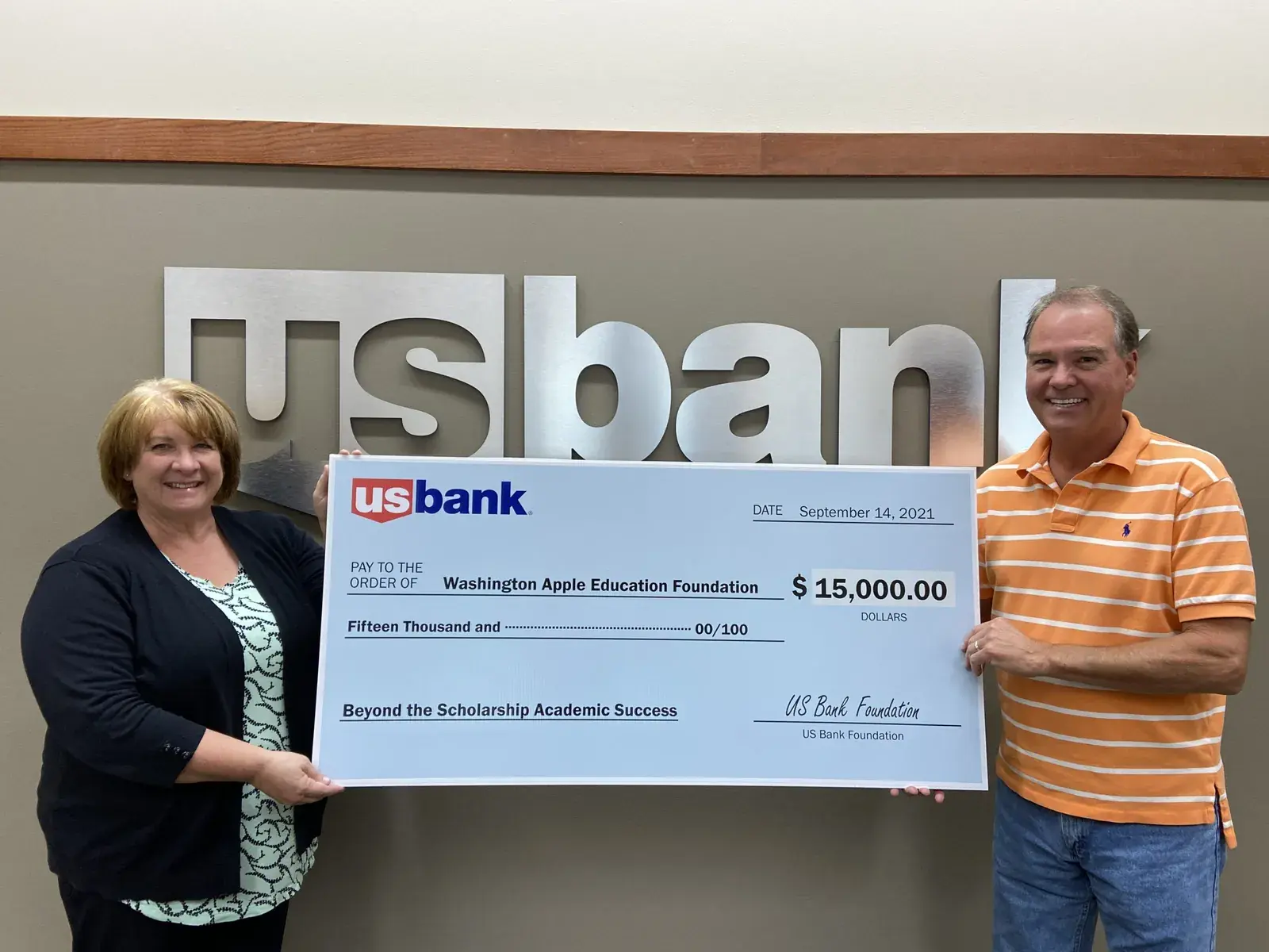 Two people holding an oversized U.S. Bank cheque for fifteen thousand dollars