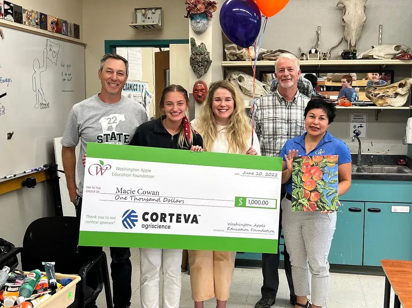 Five people in a classroom holding an oversized Corteva cheque